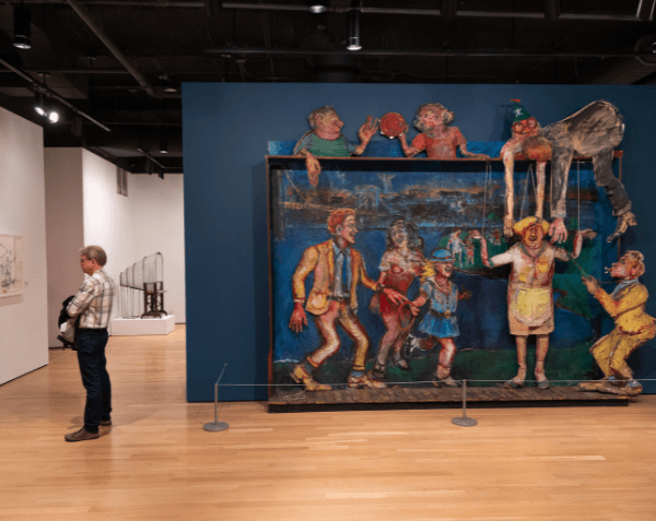 Art in an art gallery with a lone man standing to the side