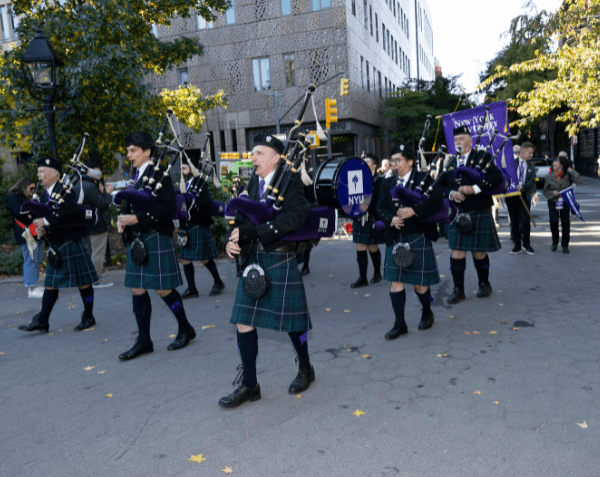 Bagpipers marching through Washington Square Park with Perstare behind them
